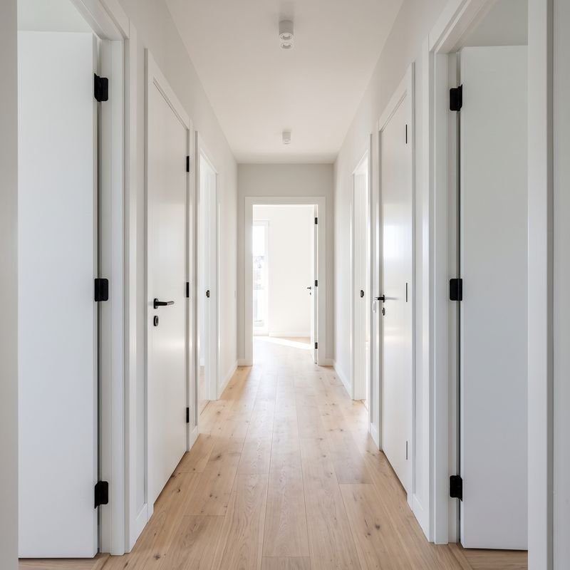 Pasillo con puertas interiores blancas lacadas nuevas y suelo de madera clara